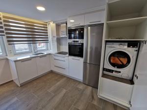 a kitchen with white cabinets and a washer and dryer at Apartamento Alfareiro in Malpica