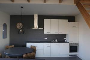 a kitchen with white cabinets and a table in it at Mooi appartement in een prachtige fiets-wandelomgeving in Abcoude