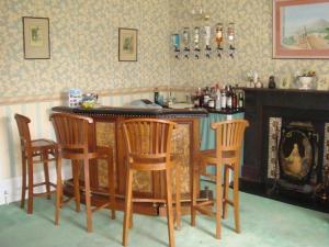 a kitchen with a bar with four chairs and a fireplace at Ingledene Guest House in Bournemouth