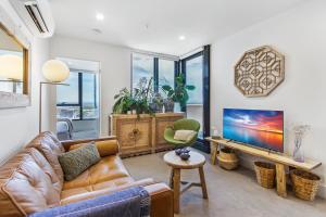 a living room with a couch and a tv at Atop the Melbourne CBD with Panoramic Views DUPLICATE in Melbourne
