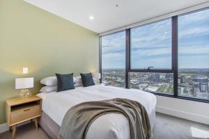 a bedroom with a white bed and large windows at Atop the Melbourne CBD with Panoramic Views DUPLICATE in Melbourne