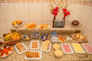 uma mesa cheia de diferentes tipos de pão e outros alimentos em Pousada Santa Cruz em Aparecida