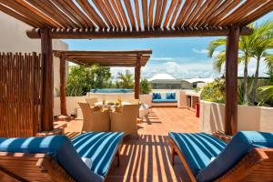 a patio with a wooden pergola and a table and chairs at Porto Playa Condo Hotel and Beach Club in Playa del Carmen