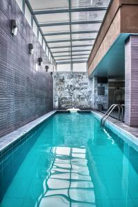 a swimming pool with blue water in a building at Casa Inn Galerias Celaya in Celaya