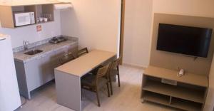 cocina con mesa con sillas y TV en Salinas Park Resort - Apartamento inteiro Frente Mar, en Salinópolis