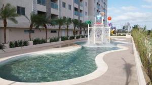 une fontaine dans une piscine en face d'un bâtiment dans l'établissement Salinas Park Resort - Apartamento inteiro Frente Mar, à Salinópolis