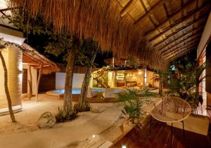 een resort met een zwembad en een rieten dak bij Mimosa Tulum in Tulum