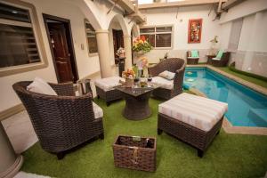 a patio with wicker chairs and a table next to a pool at Casa Lolita Hotel-Boutique in Portoviejo
