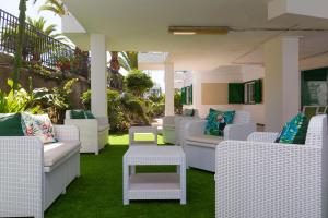 a patio with white wicker chairs and tables on grass at Apartamento Jumilla Vista Mar 22 in Playa del Ingles