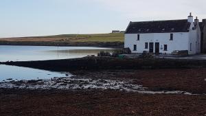 a white house sitting next to a body of water at 2 The Noust Self Catering in Saint Margarets Hope