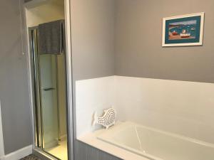 a bathroom with a shower and a bath tub at CROFT 14 SWORDALE in Swordale