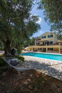 uma piscina em frente a um edifício com uma árvore em Villa Elaia Suites & Apartments No.6 em Gaios