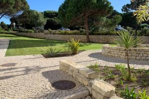 a garden with a stone wall and a stone path at Golf, Beach & Pool House in Amoreira