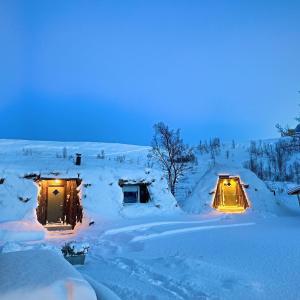 a snow covered house with lights in the snow at Modern turf house in Kokelv