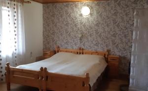 1 dormitorio con cama de madera en una habitación con papel pintado en Pensiunea Laura, en Bran