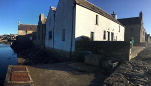 an old building sitting next to a body of water at 2 The Noust Self Catering in Saint Margarets Hope