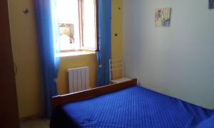 sypialnia z niebieskim łóżkiem i oknem w obiekcie Appartement a la campagne w mieście Poyanne