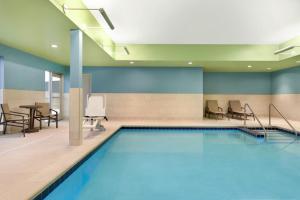 - une piscine avec des chaises et une table dans un bâtiment dans l'établissement Holiday Inn Express & Suites - Beaver Dam, an IHG Hotel, à Beaver Dam