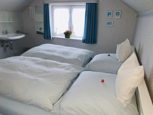 2 Einzelbetten in einem Schlafzimmer mit einem Waschbecken und einem Fenster in der Unterkunft Haus Boy Jensen Wohnung Dünenblick in Wenningstedt-Braderup