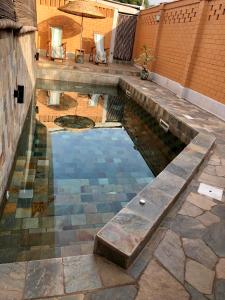 uma piscina de água com uma parede de tijolos e um guarda-chuva em Hôtel Amédzépé em Palimé