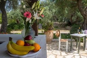 een fruitschaal op een tafel met een vaas met bloemen bij Villa Elaia Suites & Apartments No.7 in Gaios
