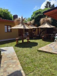 un patio con mesas y sombrillas de paja en LOS SAUCES en Mar de Ajó