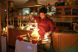a man in a kitchen with fire in a table at Hotel Zur Burg Sternberg in Extertal