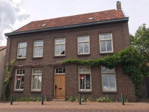 a brown brick house with a wooden door at B&B Radijs in Beegden