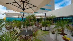 a patio with tables and chairs with plants and umbrellas at Holiday Inn & Suites - Merida La Isla by IHG in Mérida