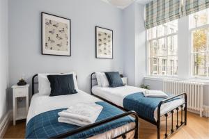 2 camas en una habitación con paredes y ventanas blancas en Luxury Royal Mile Retreat en Edimburgo