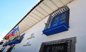 a white building with a blue balcony and flags on it at Costa del Sol Wyndham Cusco in Cusco