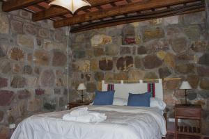 a bedroom with a bed in a stone wall at Hostal de Altura in Tilcara