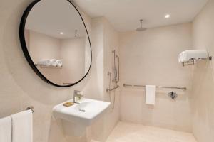 a bathroom with a sink, toilet and mirror at Hilton La Romana All- Inclusive Adult Resort & Spa Punta Cana in Bayahibe