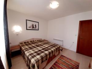a bedroom with a bed with a plaid blanket at Апартамент КАРЛИН in Pamporovo