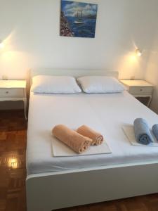 a bedroom with a white bed with towels on it at Schreng Apartments in Malinska