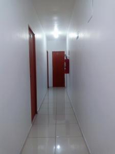a hallway with a red door and a white wall at Pousada Brasil - Self Check-in in Aparecida