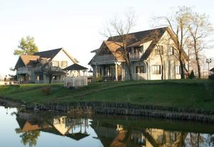 um par de casas sentadas ao lado de um corpo de água em Pastoral Resort em Velikiy Les