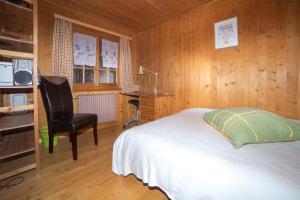 a bedroom with a bed and a chair in a room at le castor in Morgins