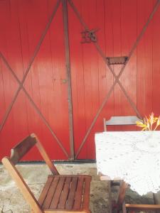 eine rote Wand mit einem Tisch, einer Bank, einem Tisch und einem Stuhl in der Unterkunft Suite Indiana Ilhabela in Ilhabela