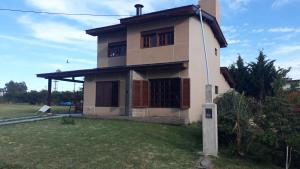 Casa amplia barrio privado Miramar في ميرامار: منزل أمامه ساحة خضراء