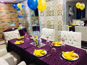 una mesa púrpura con servilletas amarillas y globos en Hotel Boutique El Poblado, en Neiva