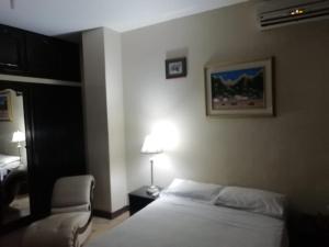 1 dormitorio con 1 cama, 1 silla y 1 lámpara en Departamentos 3 hab Manta - centro, en Manta