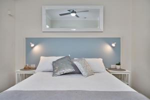 a bedroom with a white bed with a ceiling fan at Cairns Northern Beaches Holiday Retreat in Clifton Beach