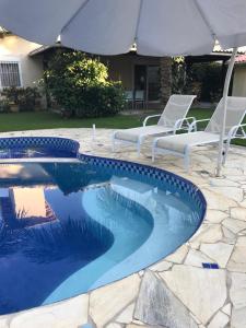 una piscina con 2 sillas y una sombrilla en Búzios Beach House, en Búzios