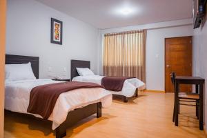 a hotel room with two beds and a table at Hotel Puñuykuna - Cajamarca in Cajamarca
