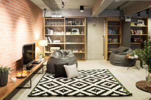 a living room with a couch and a television at BED STATION Hostel Ratchthewi in Bangkok