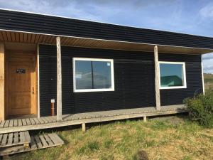 a black house with a wooden porch and a door at Cielo Austral in Puerto Natales