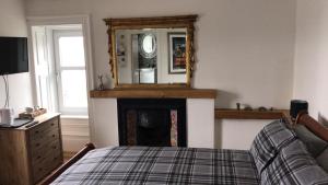 um quarto com uma cama e um espelho sobre uma lareira em Fasgadh Rooms em Tarbert