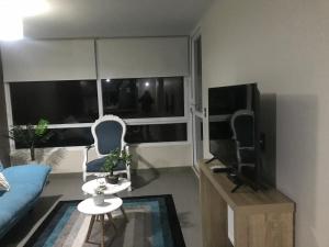 un salon avec un canapé bleu et une télévision dans l'établissement Departamento La Serena, Laguna del Mar, Vista Privilegiada, à La Serena