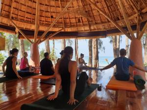 um grupo de pessoas sentadas em uma aula de yoga em Long Beach Chalet - SHA Extra Plus em Ko Lanta